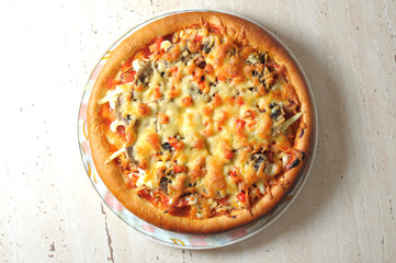 Baked homemade pizza on a white dish on wooden table