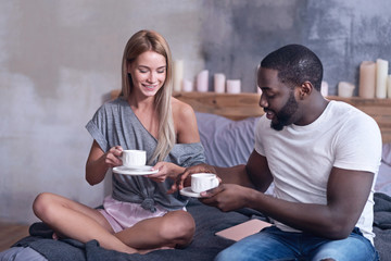 Cheerful international couple enjoying tea at home