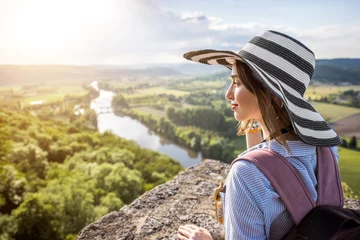 Foto op Canvas Young woman tourist in hat enjoying sunset view on the beautiful landscape with Dordogne river in France © rh2010