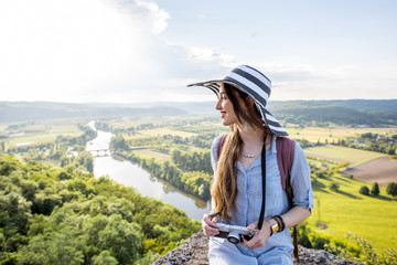 Young woman tourist in hat enjoying sunset view on the beautiful landscape with Dordogne river in France - obrazy, fototapety, plakaty