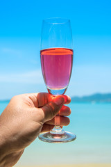 Man hand with glass of champagne by the sea.
