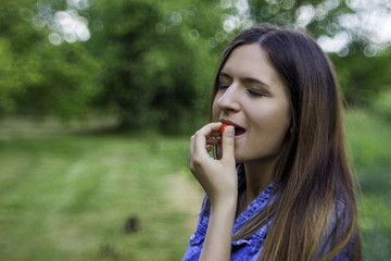 Fototapeta premium Attractive young woman holding cherry open mouth background summer