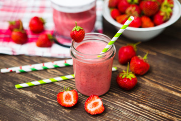 Healthy strawberry smoothie in mug with checkered cloth against rustic wood.