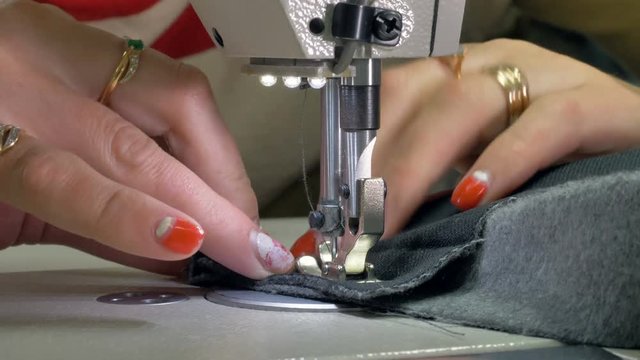 A tailor slowly sewing a short thick fabric. 