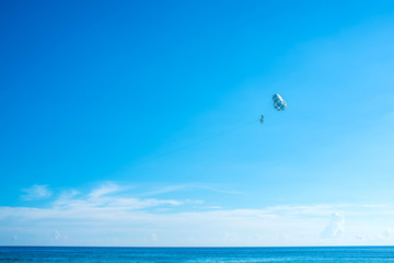 Naklejka na ściany i meble Flying parasailing in a blue sky,Phuket,Thailand.