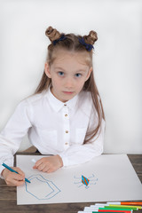 Close up of little girl in white blouse which is focused on drawing. Preschooler is learning how to draw. Kindergarten and school. Family fun.