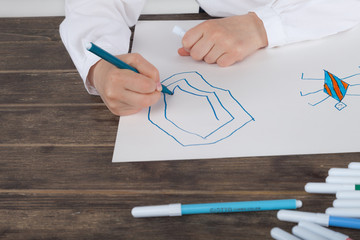 Close up of a hand of little girl in white blouse which is focused on drawing. Preschooler is learning how to draw. Kindergarten and school. Family fun.