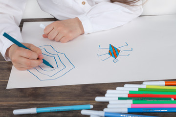 Close up of a hand of little girl in white blouse which is focused on drawing. Preschooler is learning how to draw. Kindergarten and school. Family fun.