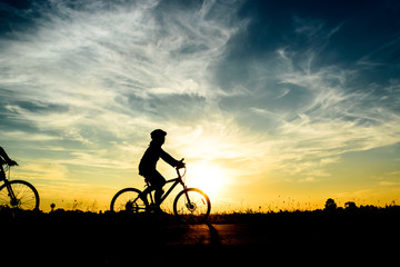 Silhouette of cyclist riding on  bike at sunset.