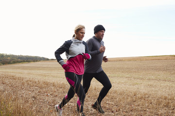 Mature Couple Running Around Autumn Field Together