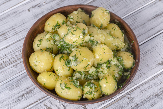 Boiled potatoes with dill, garlic and butter in a plate on wooden table