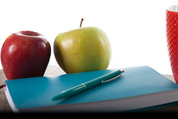 Turquoise notepad with pen, apples and cup.  Work and study environment. 
