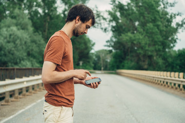 Hipster tourist using cellphone on bridge background. Male hands holding gadget, mockup copy space for text message design