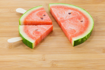 Tiny watermelon popsicle shaped and sliced on bamboo tablet