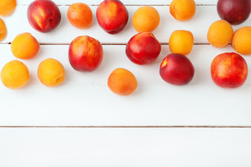 Naklejka na ściany i meble white wooden background with juicy orange apricots and bright fresh red necratins and peaches. Colorful composition of healthy fruits. Food vegetarian nutrition concept. Horizontal background.