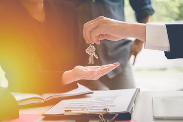 Hands of estate agent giving keys to the couple