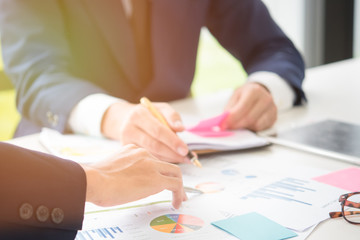 Businessman and partner hands holding pen pointing graph chart, calculator and post it note for Plans to improve quality next month.