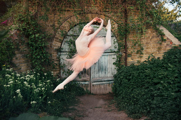 Ballerina dancing outdoors classic ballet poses in urban background