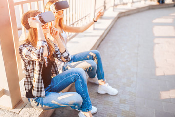 Obraz na płótnie Canvas Two pretty girls enjoy virtual reality glasses outdoor
