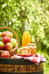 Basket of apples on background orchard standing on a barrel. Apple juice and apple preserves.