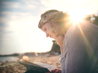 Junge Frau ließt ein Buch am Strand im Sonnenschein - Mallorca Spanien