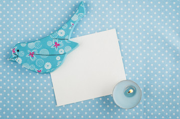 Blue napkin, card, wooden bird and candle, space for text