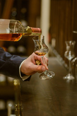 Sommelier pouring wine into glass from mixing bowl. Male waiter