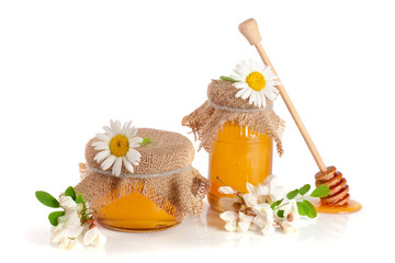 Jar of honey with flowers of acacia and chamomile isolated on white background