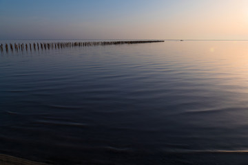 Golden lake surface at sunset  / Abandoned destroyed wooden pier in lake at sunset