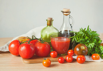 Tomatoes, tomato juice, parsley and bottles on a wooden table.