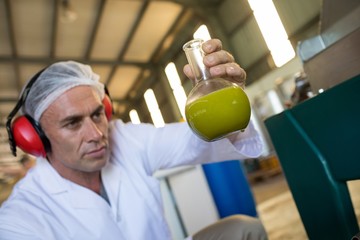 Technician examining olive oil produced from machine
