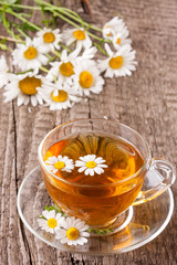 Obraz na płótnie Canvas Herbal tea with fresh chamomile flowers on old wooden background