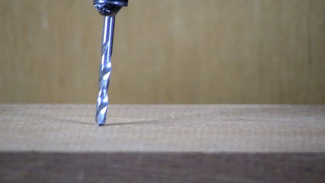 A hole is drilled into maple board with cordless drill & countersink bit.  Sawdust is then blown away.  Macro shot from slight high angle looking down with wood background.  Audio included in clip