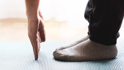 Obraz premium Adult person doing some yoga and meditation exercises on a mat in a class. Empty copy space for Editor's text.