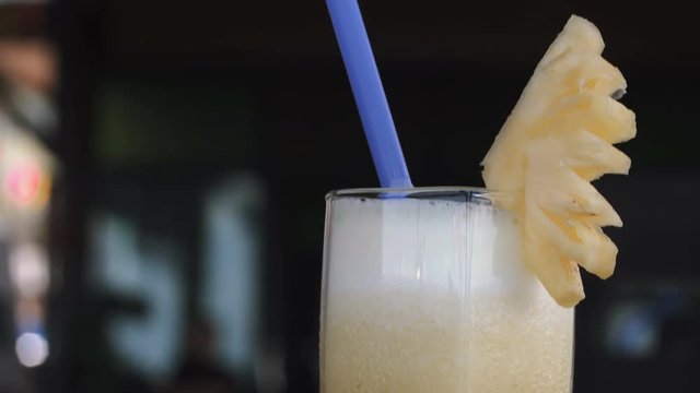 Female drinking pineapple cocktail. Piece of fruit and straw, a close-up mouth and a glass.