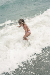 Girl enjoying the summer on the beach , playing in beautiful blue sea. Child playing on the waves.