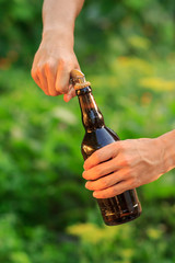 Young man opening bottle of beer with old opener