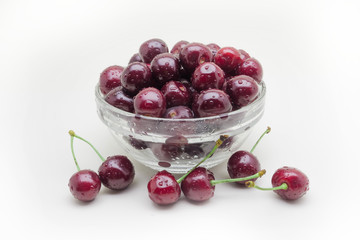 Glass vase with crumbling cherries isolated on white background