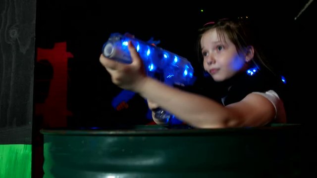 Kid hides behind a barrel and shoots a lasertag weapon