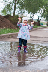 Little girl jumping in the puddle