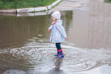 Little girl jumping in the puddle