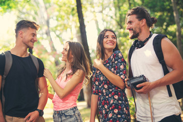 Group of friends or couples having fun with photo camera in summer park