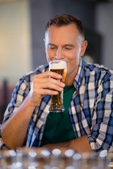 Smiling man having glass of beer at counter