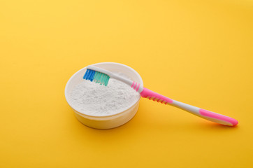 Tooth powder and toothpaste on a yellow background. Care of the oral cavity. Teeth whitening.
