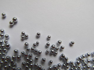 Small shiny metallic balls on white hard paper background