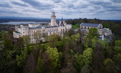 Fototapeta na wymiar Aerial view on most beautiful, fairytale Czech castle, neo-gothic castle Huboka.Famous, like Wndsor chateau placed in a large English park. View from park side against dramatic sky. Czech landscape.