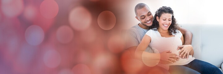 Man with hands on wife's stomach with red bokeh transition