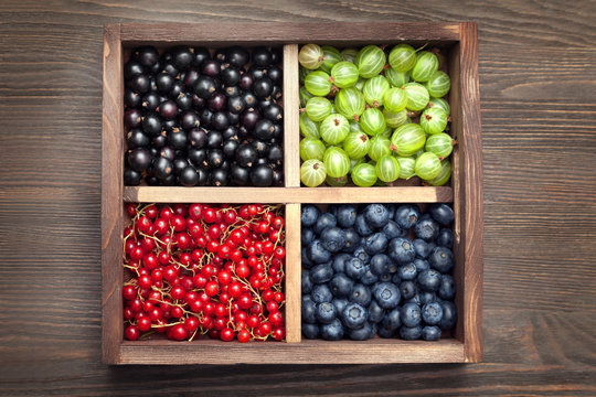 Red black currant blueberry gooseberry in a wooden box on an old table