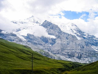 Fototapeta na wymiar Landscape view of Swiss alps snow covered mountains and green hills