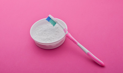 Tooth powder and toothpaste on a pink background. Care of the oral cavity. Teeth whitening.

